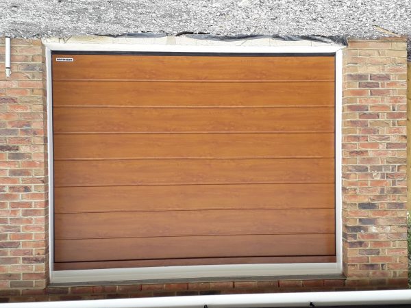 Ribbed golden oak garage door with white surrounding.