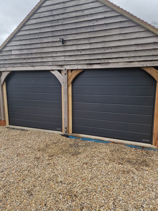 Two new black garage doors installed with wooden frame.