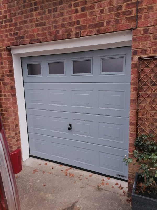 White framed panelled light grey garage door with windows.