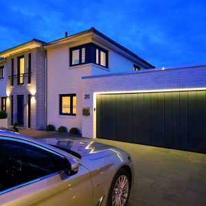 Dark grey Hormann sliding garage door featuring integrated lighting, and a silver car parked in the driveway.