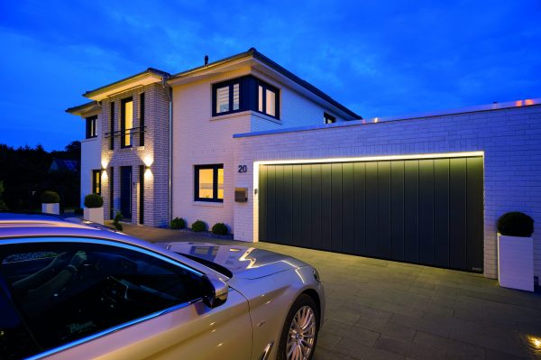 Dark grey Hormann sliding garage door featuring integrated lighting, and a silver car parked in the driveway.